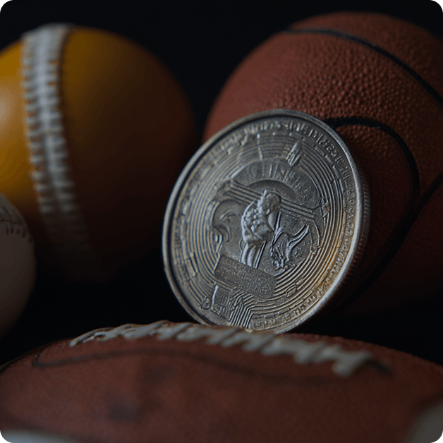 close-up of a metallic coin featuring an athlete emblem resting on sports balls, representing tokenization and ownership of digital sports assets